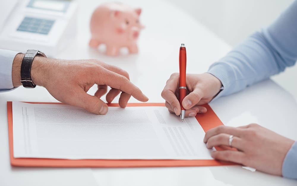 Ein Vertrag auf einem Schreibtisch der unterschrieben wird - Immobilienverkauf